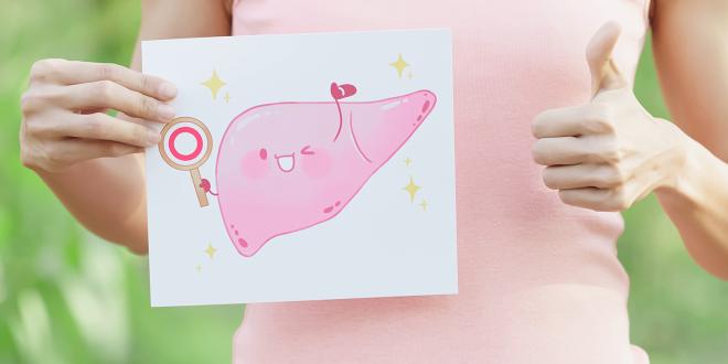 a woman holding a cartoon illustration of a happy, healthy liver