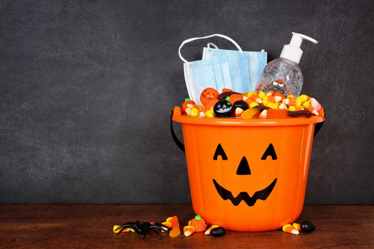 a trick or treat pail with sanitizer and a mask