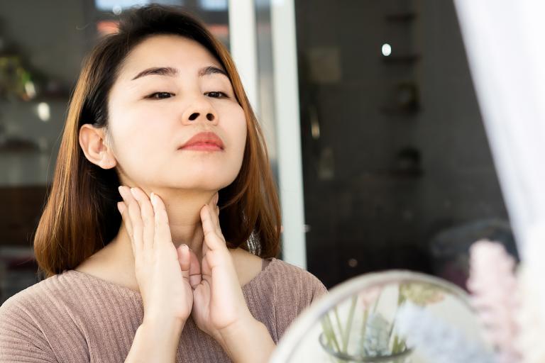 a woman rubbing her nodes on her neck below her jaw